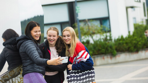 kolme tyttöä ottaa selfietä koulun pihalla. Image Tero Takalo-Eskola