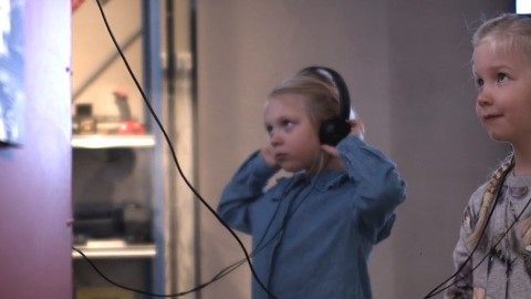 Children wearing headphones in the Exploring Central Finland exhibition.. Kuva Keski-Suomen museo (KeMu)