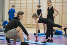 Ohjaaja ohjaa lasta liikunnassa salissa. Kuva Jyväskylän Urheiluakatemia