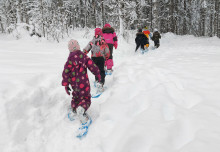 Kuusi lasta kulkee jonossa lumikengät jalassa metsässä / Satu Jokilahti. Kuva Satu Jokilahti